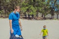 Volunteer blue face mask forest sand beach. Active father wait son help pick up garbage into black bag. Problem spilled