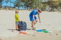 Volunteer blue face mask forest sand beach. Son helps father hold black bag for pick up garbage. Problem spilled rubbish