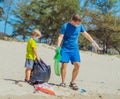 Volunteer blue face mask forest sand beach. Son helps father hold black bag for pick up garbage. Problem spilled rubbish