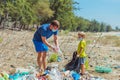 Volunteer blue face mask forest sand beach. Son helps father hold black bag for pick up garbage. Problem spilled rubbish