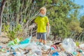 Volunteer boy in face mask helps to pick up garbage which pollute beach near forest. Problem of spilled rubbish trash