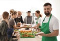 Volunteer with colleague giving food to poor people Royalty Free Stock Photo