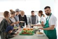 Volunteer with colleague giving food to poor people Royalty Free Stock Photo