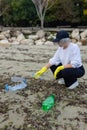 volunteer collecting plastic bottles on a polluted beach, highlighting ocean Royalty Free Stock Photo