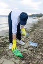 volunteer collecting plastic bottles on a polluted beach, highlighting ocean Royalty Free Stock Photo
