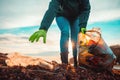 A volunteer collects garbage on a muddy beach. Close-up. The concept of Earth Day. Bottom view Royalty Free Stock Photo