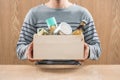 Volunteer with donation box with food stuffs on wooden background