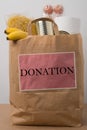 Volunteer with donation box with foodstuffs. Male hands hold a set of food products in a paper bag