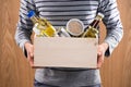 Volunteer with donation box with foodstuffs on wooden background