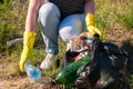 Volunteer girl in yellow gloves collects garbage