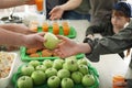 Volunteer giving apple to poor woman indoors Royalty Free Stock Photo