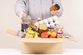 Volunteer hands with food donation box full of grocery products on white desk