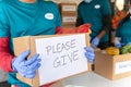 Volunteer holding donation box with please give signage message - Concept of requesting people for social service, Charity work