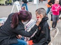 Volunteer paints apple on young boy's face