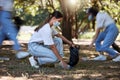 Volunteer, recycle and reduce waste by picking up litter, dirt and garbage outdoors in a park during covid. A young team