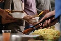 Volunteer serving food to poor people in charity centre Royalty Free Stock Photo