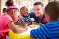 Volunteer teacher helping a class of preschool kids drawing Royalty Free Stock Photo