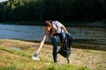 Volunteer woman collecting plastic rubbish on coast of the river. Cleaning environment concept