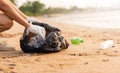 Volunteer woman picking plastic bottle into trash plastic bag black for cleaning the beach