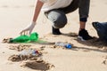 Volunteer woman picking plastic bottles into trash plastic bag for cleaning the beach and coastal zone