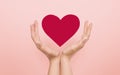 Volunteering concept. Female hands guarding red heart over pink background, collage