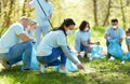 Volunteers in masks cleaning park from garbage