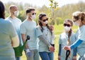 Group of volunteers in masks with tree seedling