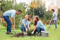 Volunteering. Young people volunteers outdoors planting trees digging ground talking cheerful