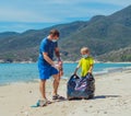 Volunteers blue face mask paradise beach sand lazur sea. Father son pick up garbage into black bag. Problem spilled