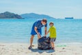 Volunteers blue face mask paradise beach sand lazur sea. Father son pick up garbage into black bag. Problem spilled