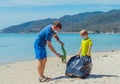 Volunteers blue face mask paradise beach sand lazur sea. Father son pick up garbage into black bag. Problem spilled