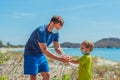 Volunteers in blue medical face mask. Father puts gloves on his son for pick up garbage which pollute beach near sea