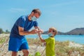 Volunteers in blue medical face mask. Father puts gloves on his son for pick up garbage which pollute beach near sea