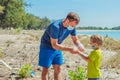 Volunteers in blue medical face mask. Father puts gloves on his son for pick up garbage which pollute beach near sea