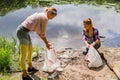 Volunteers cleaning garbage near river. Women picking up a bottle plastic in the lake, pollution and environment Royalty Free Stock Photo