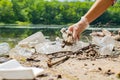 Volunteers cleaning garbage near river. Women picking up a bottle plastic in the lake, pollution and environment