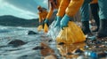 Volunteers cleaning up the beach, collecting bottles in a big plastic bag. Royalty Free Stock Photo