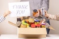 Volunteers collect grocery products to food donation box and holding paper sheet with message Thank you