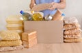 Volunteers collecting food into donation box. Pasta, oil, canned food, condensed milk, cookies, sugar, dinner for the needy. Royalty Free Stock Photo