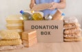 Volunteers collecting food into donation box. Pasta, oil, canned food, condensed milk, cookies, sugar, dinner for the needy. Royalty Free Stock Photo