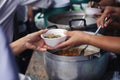 Volunteers giving food to poor people in desperate need : The concept of food sharing Help solve Hunger for the homeless Royalty Free Stock Photo