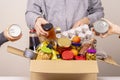 Volunteers hands collecting grocery products, foodstuff to food donations box