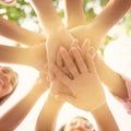 Volunteers putting hands together outdoors on sunny day