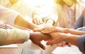 Volunteers putting hands together at table in sunlit room