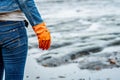 Volunteers wear jeans and long sleeved shirts and wear orange rubber gloves to collect garbage on the beach. Beach environment. Royalty Free Stock Photo