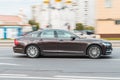 Volvo S90 D5 on the city street in motion. Brown Volvo S90 rides on the road, side view