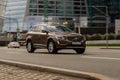 Volvo XC60 SUV in motion. Brown crossover is fast driving on city street. Front side view of car rushing on urban road