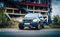 Volvo XC90 SUV stands on the street against the background of an abandoned industrial building with stairs and open areas on an au