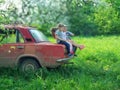 Voroblevychi village, Drohobych, Ukraine - May 29, 2018: Children sits on trunk of old car, the natural environment