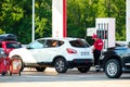 A female tanker in uniform refueling a car at a gas station. Royalty Free Stock Photo
